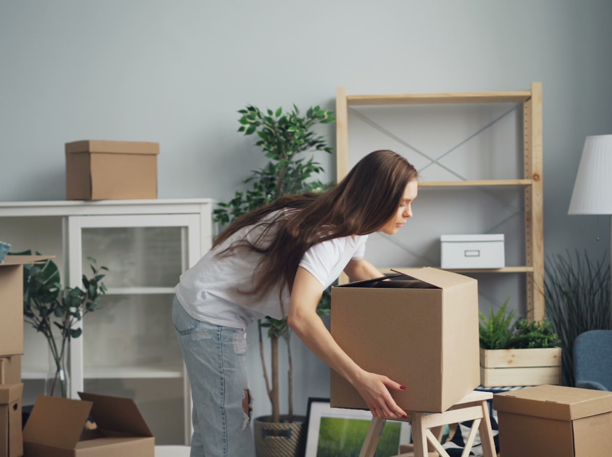 Packing household belongings into moving boxes in a living room