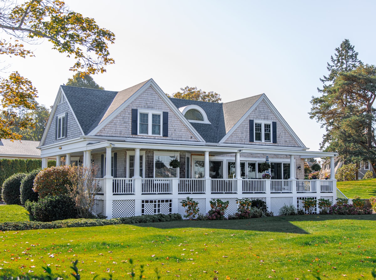 A clapboard home with a wrap-around porch on an autumn afternoon
